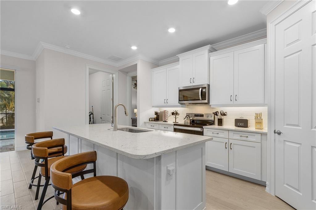 Kitchen with white cabinetry, sink, an island with sink, and stainless steel appliances