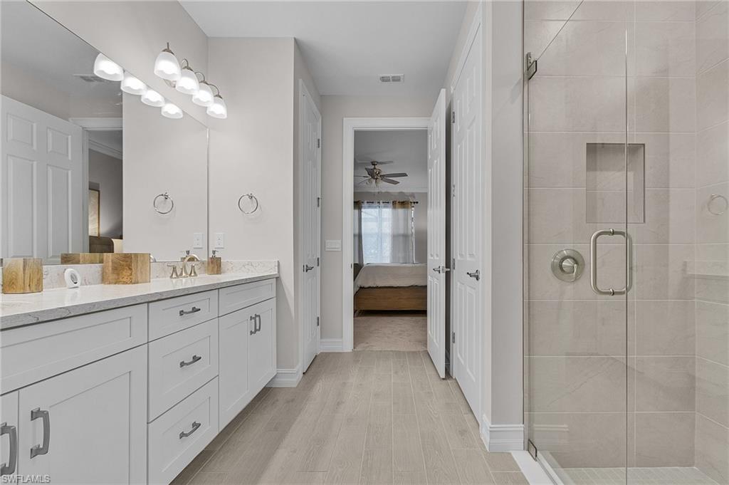 Bathroom with ceiling fan, hardwood / wood-style floors, vanity, and a shower with shower door