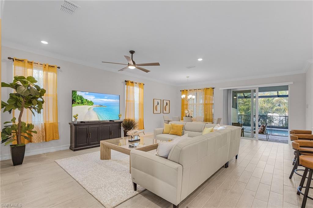 Living room with ceiling fan with notable chandelier, light hardwood / wood-style flooring, and crown molding
