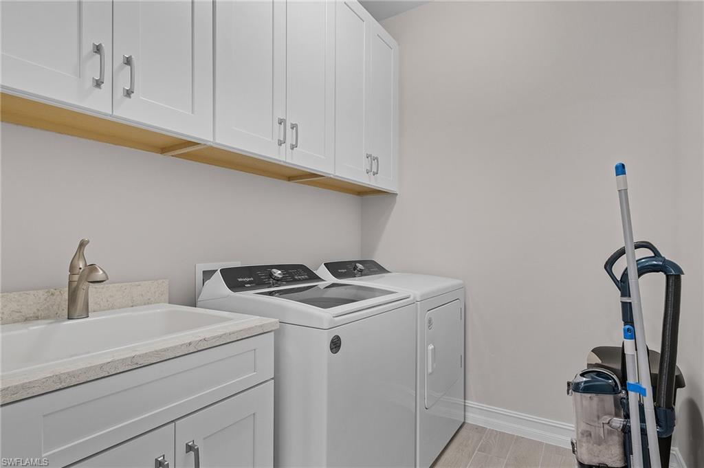 Washroom with cabinets, independent washer and dryer, light hardwood / wood-style flooring, and sink