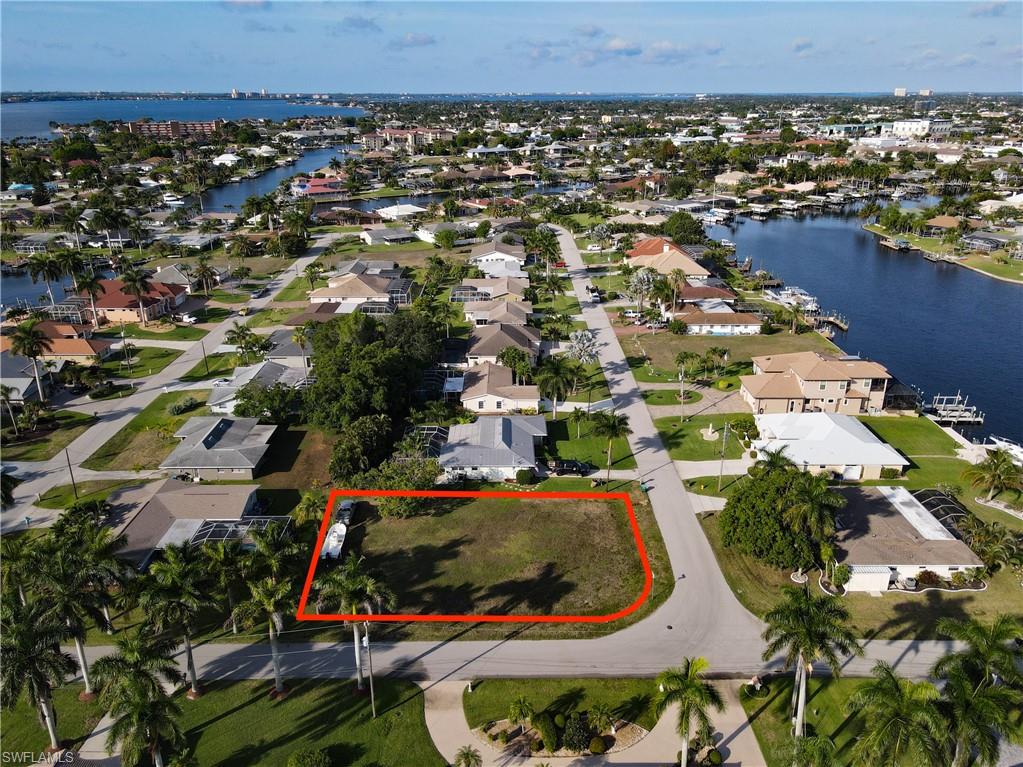 Aerial view of residential area with property boundaries highlighted and a large body of water