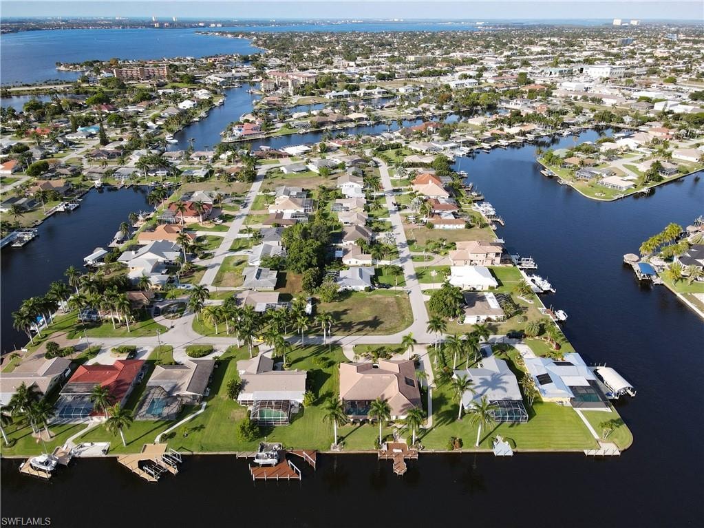 Aerial view of property and surrounding area featuring nearby suburban area and a nearby body of water