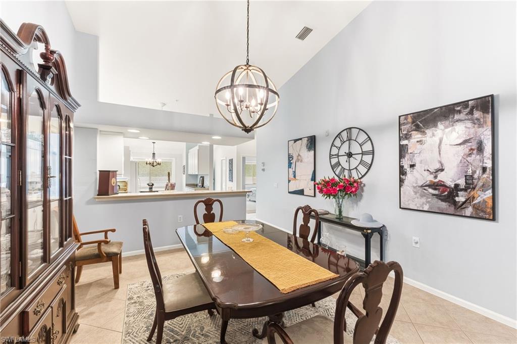 Dining room with a chandelier, vaulted ceiling, and light tile patterned floors
