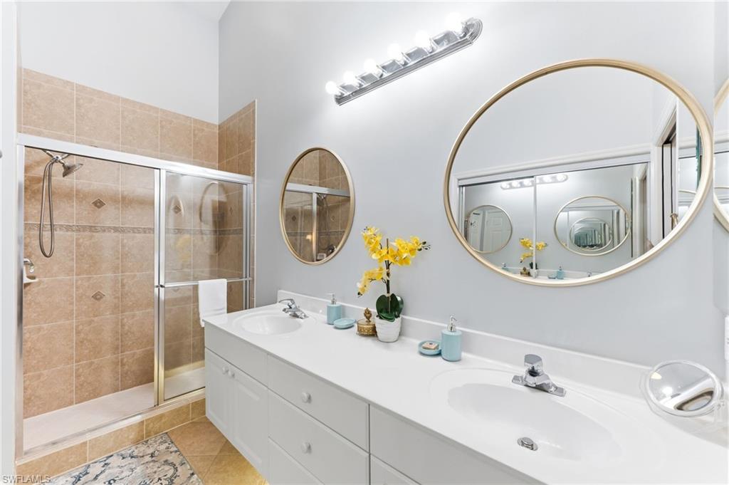 Full bathroom featuring double vanity, a shower stall, and light tile patterned floors