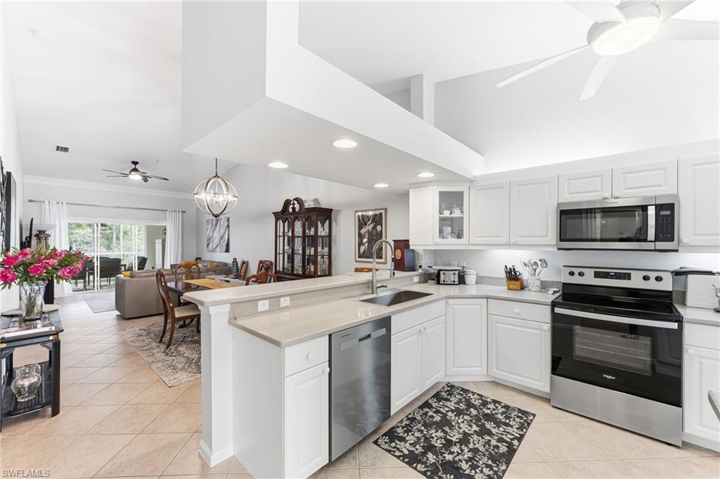 Kitchen with ceiling fan, stainless steel appliances, a peninsula, white cabinetry, and vaulted ceiling