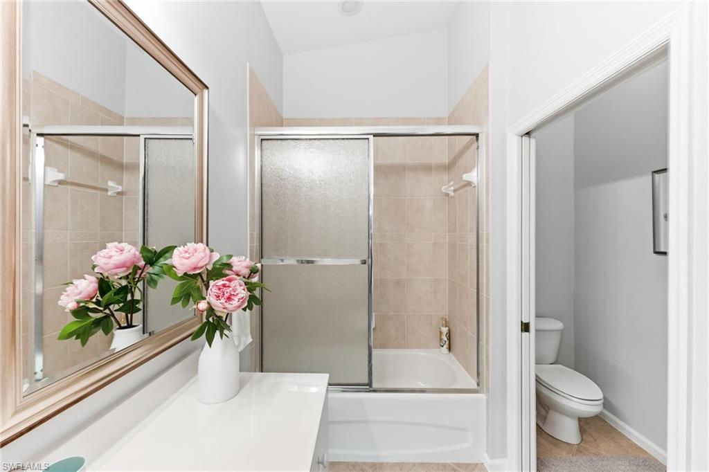 Bathroom with vanity, bath / shower combo with glass door, and light tile patterned floors