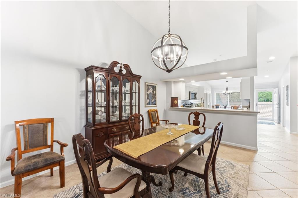 Dining space featuring suspended lighting, light tile patterned flooring, and vaulted ceiling