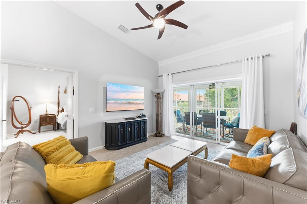 Living area featuring vaulted ceiling, a ceiling fan, light tile patterned floors, and ornamental molding