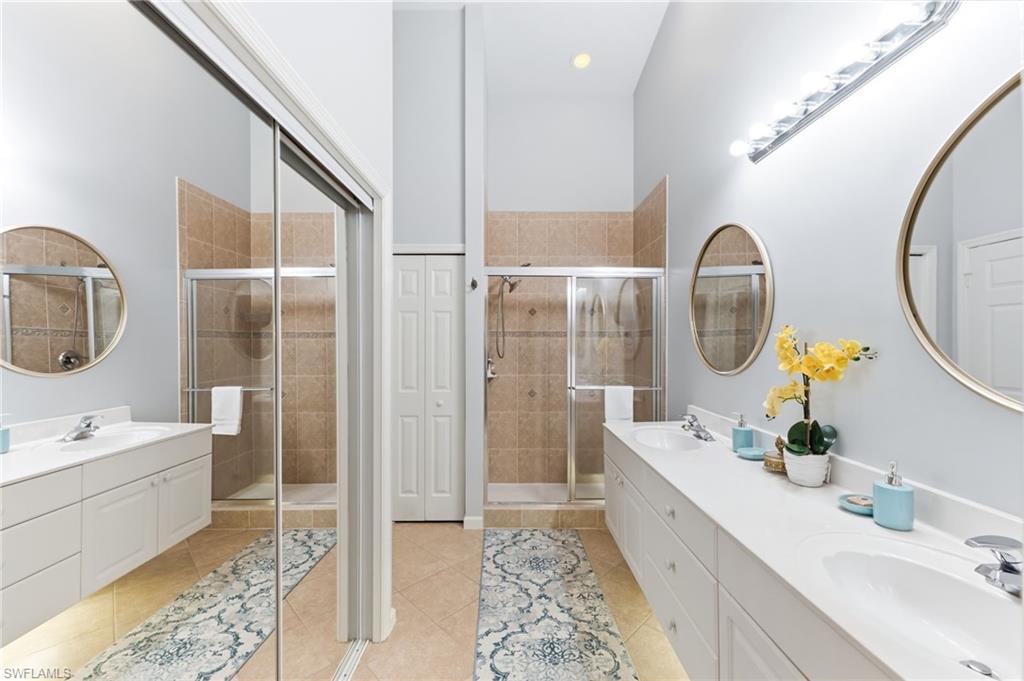 Full bathroom with double vanity, light tile patterned floors, a stall shower, recessed lighting, and a closet