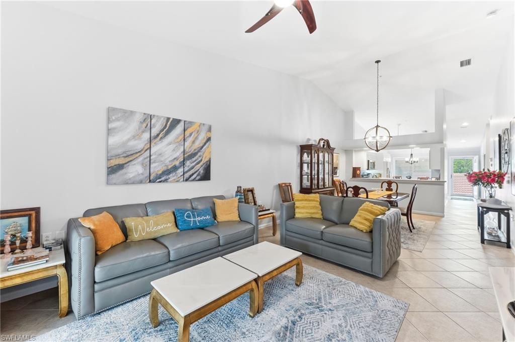 Living area featuring light tile patterned floors, ceiling fan, vaulted ceiling, and hanging lights