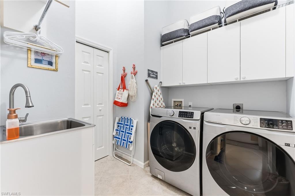 Laundry area featuring washing machine and dryer, cabinet space, and light tile patterned floors