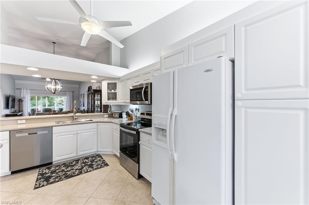 Kitchen with stainless steel appliances, white cabinetry, ceiling fan, a chandelier, and glass fronted cabinets