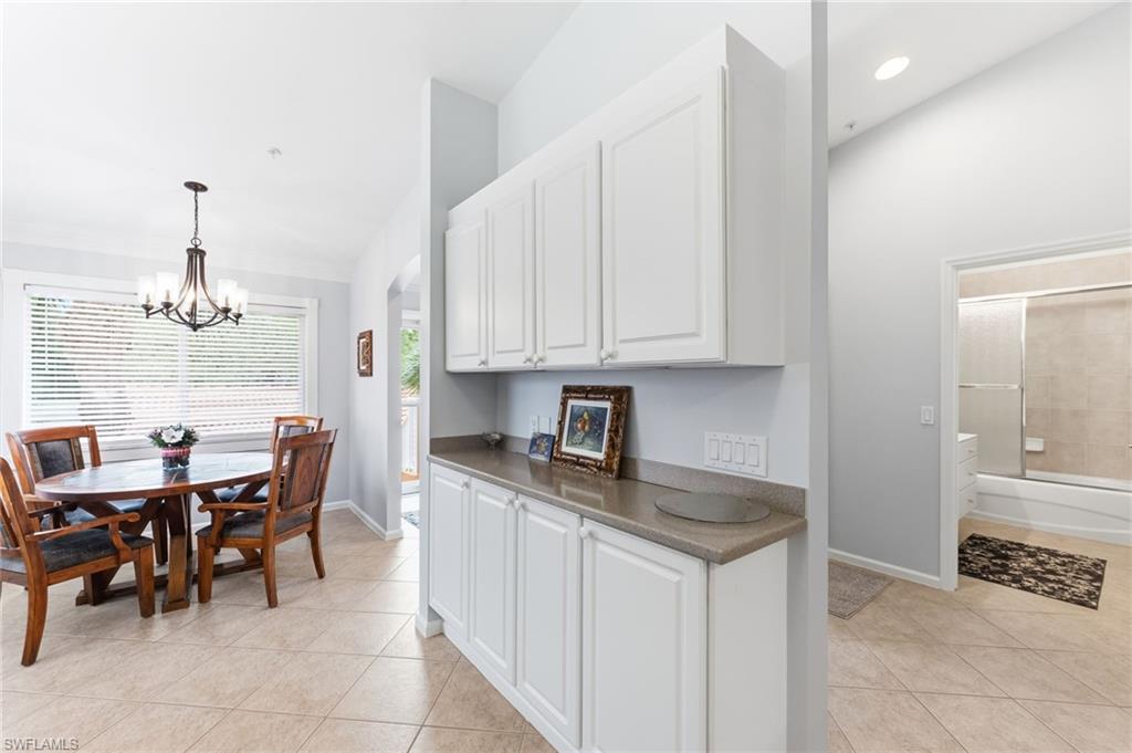 Kitchen featuring light tile patterned floors, white cabinetry, dark countertops, a chandelier, and arched walkways