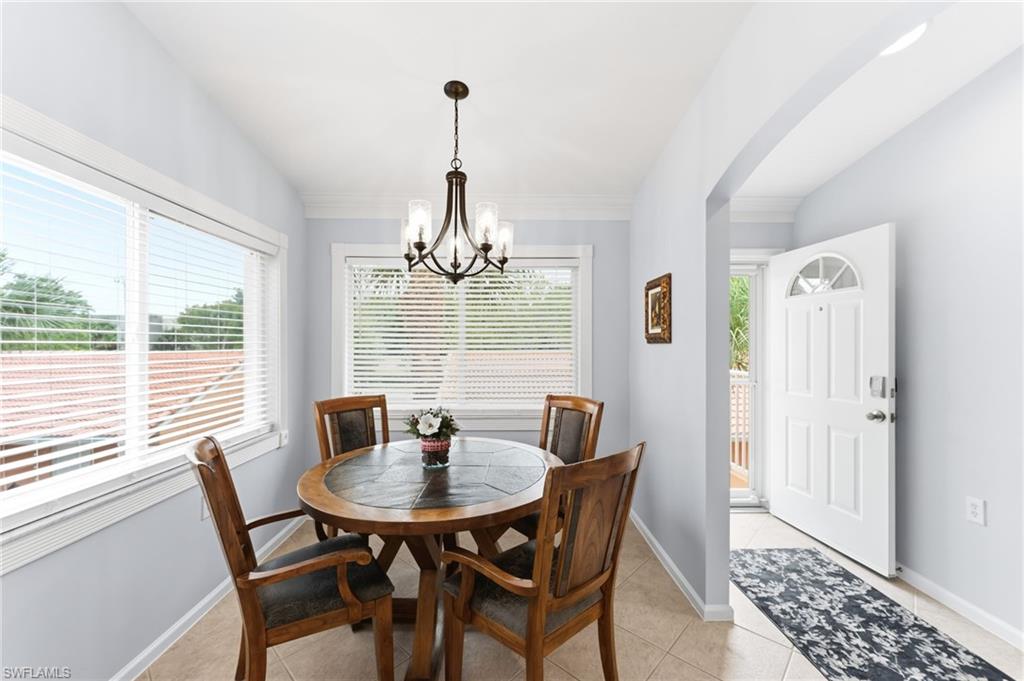 Dining area featuring vaulted ceiling, light tile patterned flooring, hanging lights, and arched walkways
