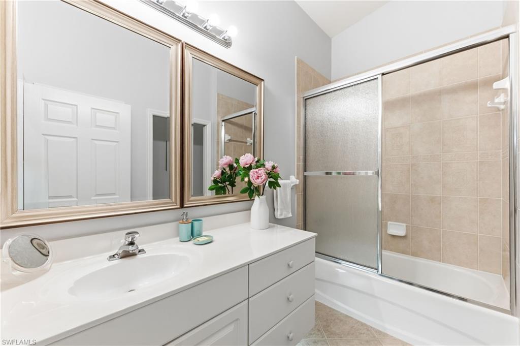 Bathroom with vanity, enclosed tub / shower combo, and light tile patterned floors