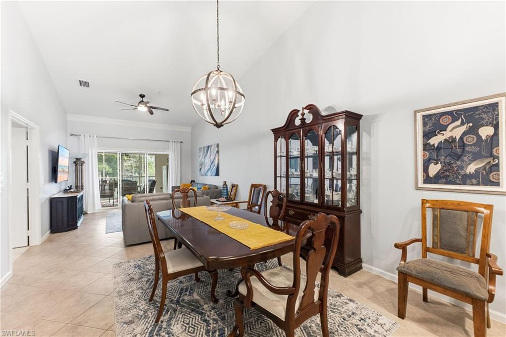 Dining room featuring vaulted ceiling, ceiling fan, hanging lights, and light tile patterned floors