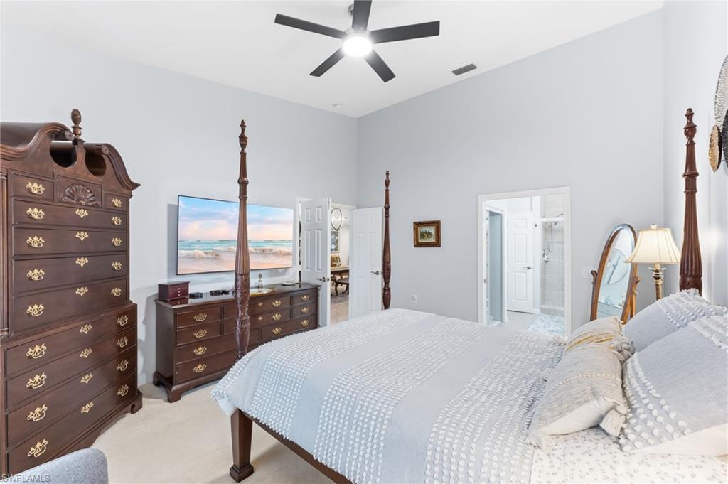 Bedroom featuring light colored carpet, a high ceiling, and a ceiling fan