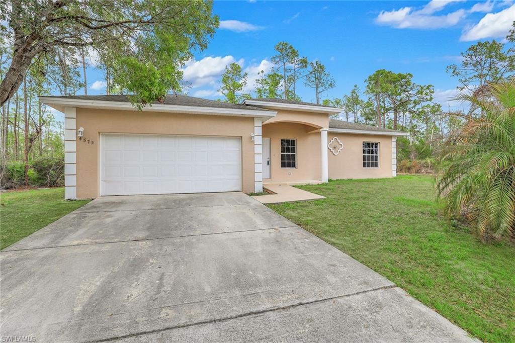 Single story home with a front yard, concrete driveway, stucco siding, and a garage