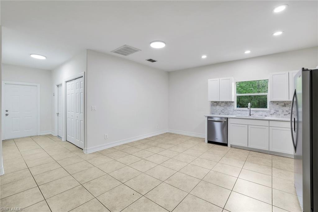 Kitchen with white cabinets, stainless steel appliances, tasteful backsplash, light tile patterned floors, and recessed lighting