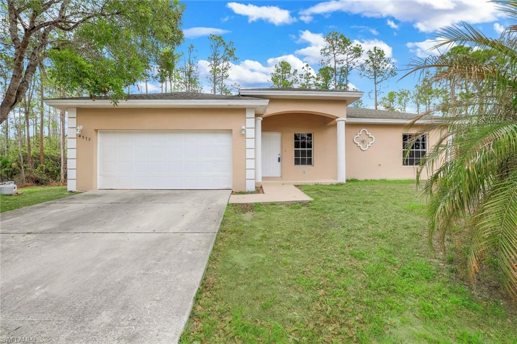 View of front of home with stucco siding, an attached garage, driveway, and a front lawn