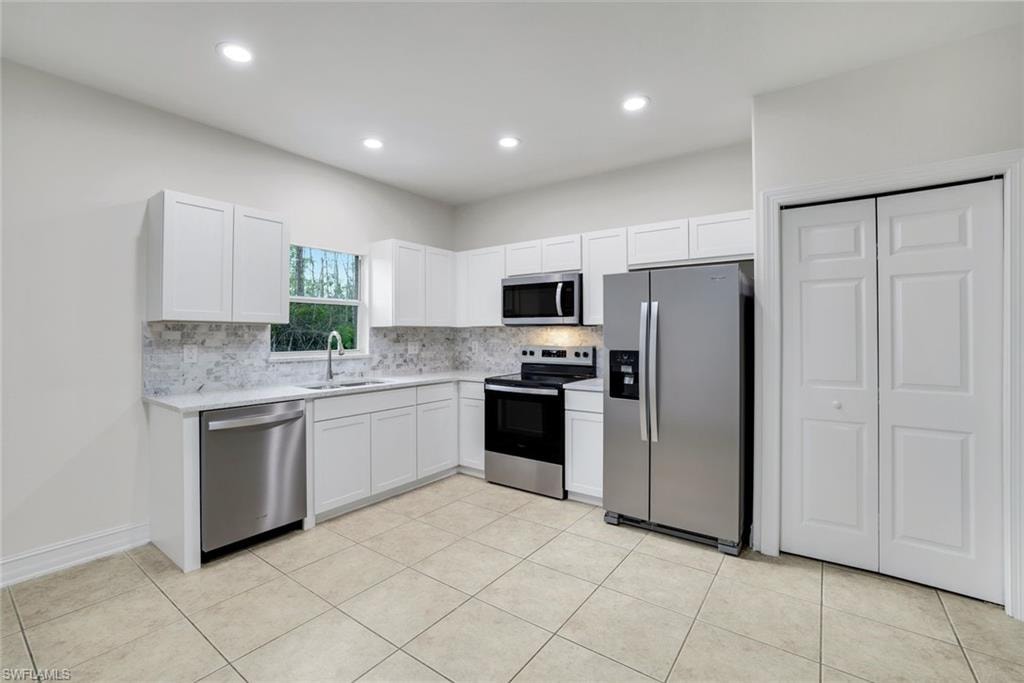 Kitchen with stainless steel appliances, white cabinetry, decorative backsplash, recessed lighting, and light tile patterned floors