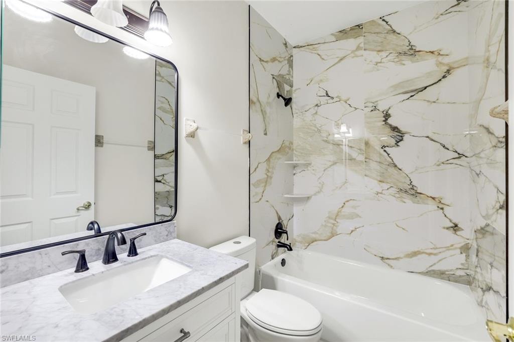 Bathroom with vanity and a combined bath / shower with marble appearance