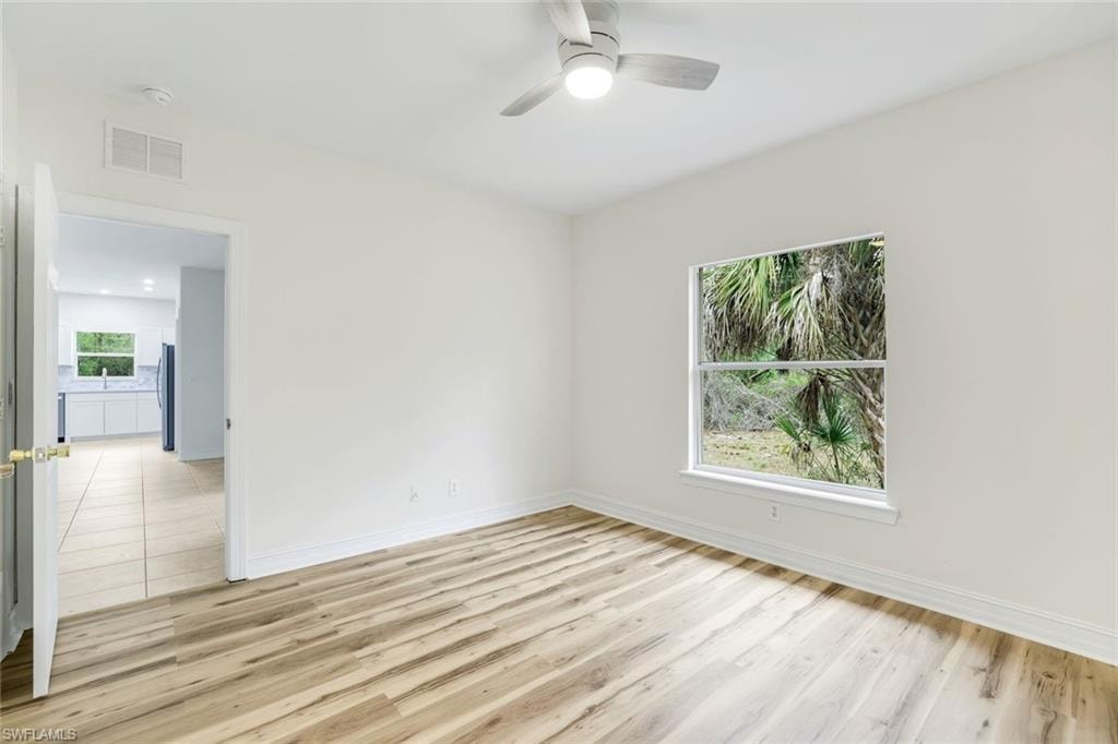 Unfurnished room featuring light wood-style floors, a ceiling fan, and healthy amount of natural light