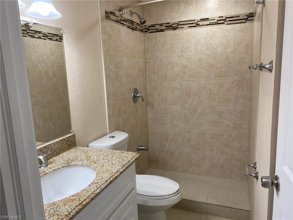 Bathroom with a textured wall, vanity, and a shower stall