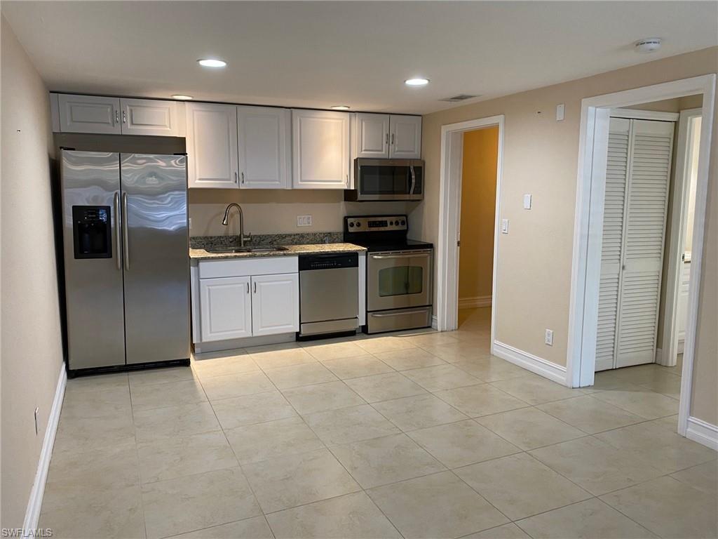 Kitchen featuring stainless steel appliances, recessed lighting, white cabinetry, light tile patterned floors, and dark stone countertops