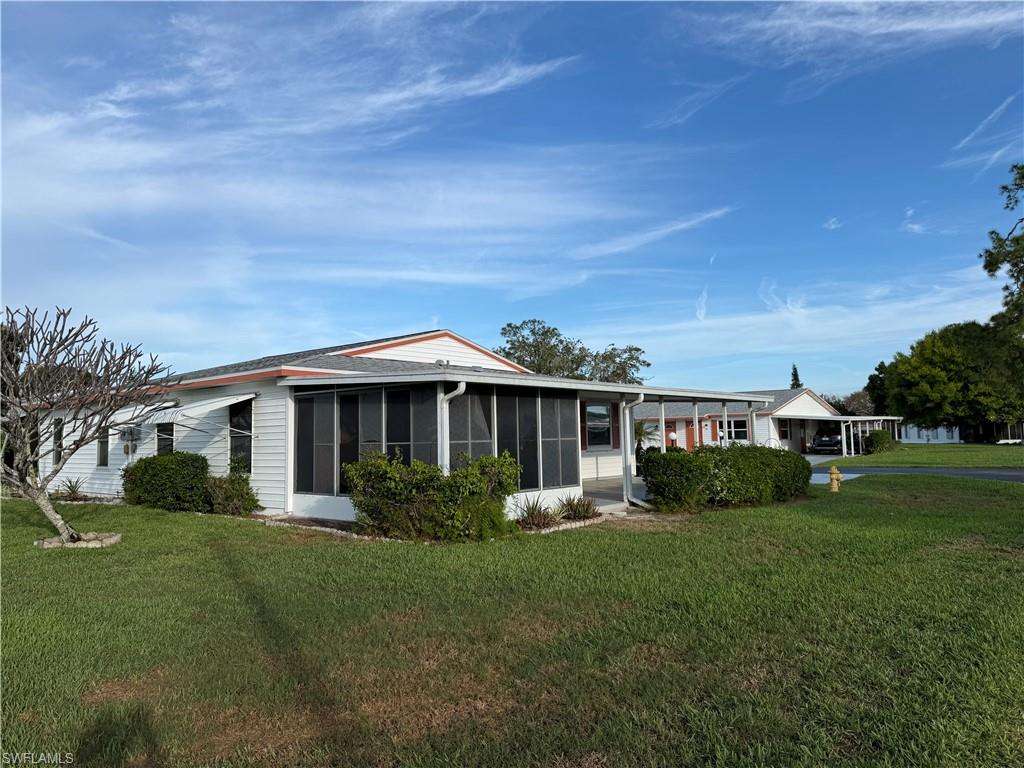 View of front of house featuring a front yard, a carport, and a sunroom