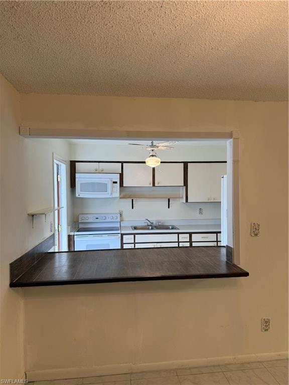 Kitchen featuring white stove, white cabinetry, a textured ceiling, a peninsula, and ceiling fan