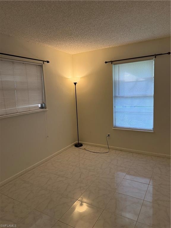 Empty room featuring a textured ceiling and baseboards