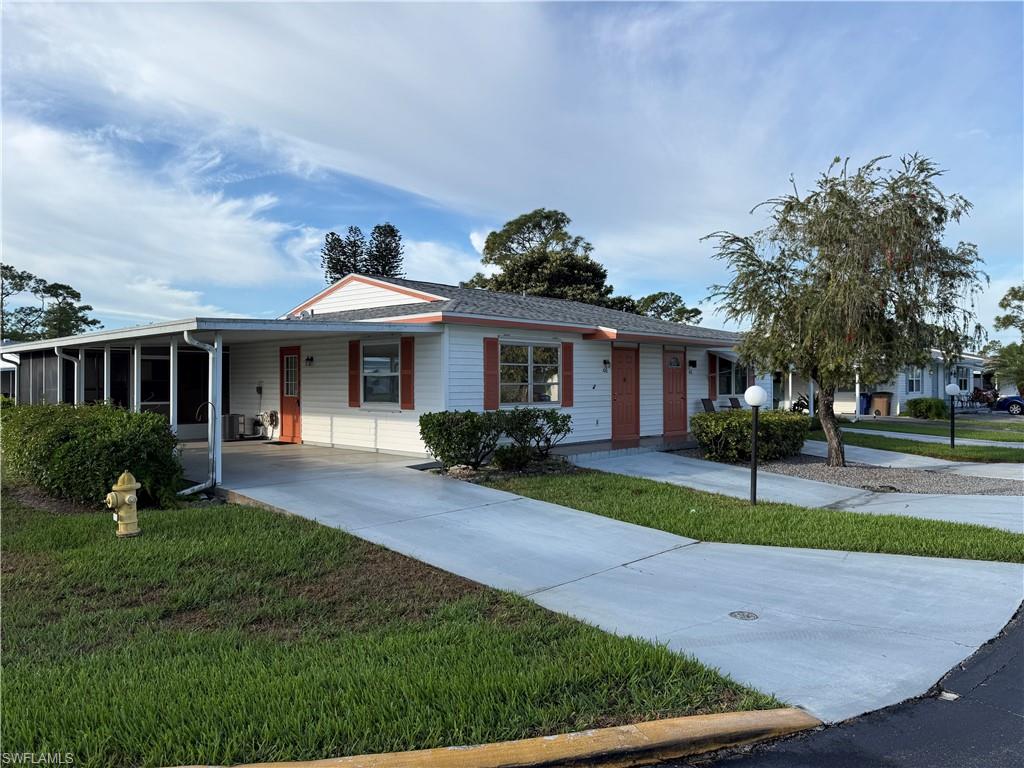 Ranch-style home featuring driveway, a front yard, an attached carport, and covered porch