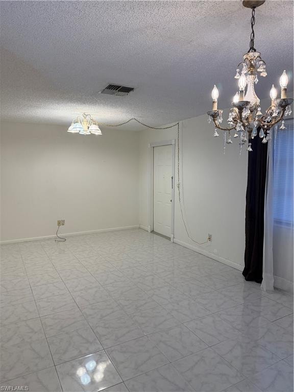 Spare room featuring suspended lighting and a textured ceiling