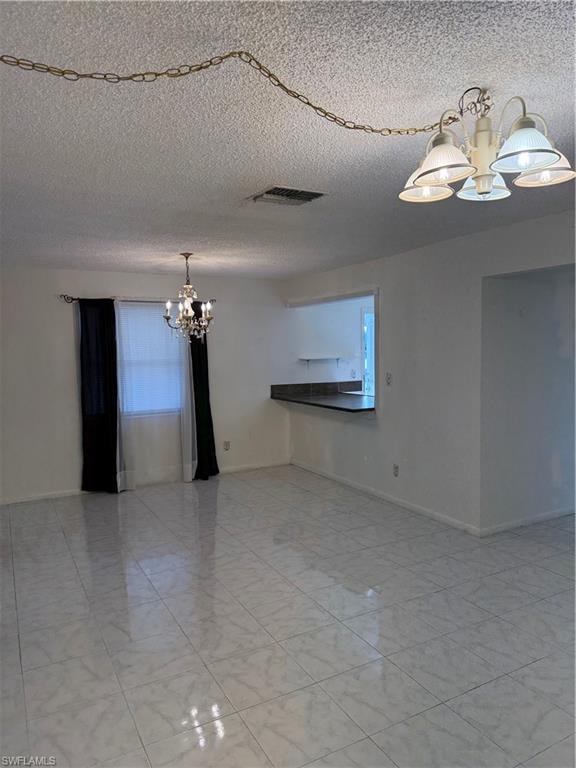 Empty room with hanging lights and a textured ceiling