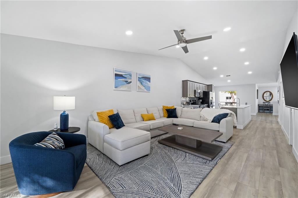 Living room featuring light wood-style floors, lofted ceiling, ceiling fan, and recessed lighting