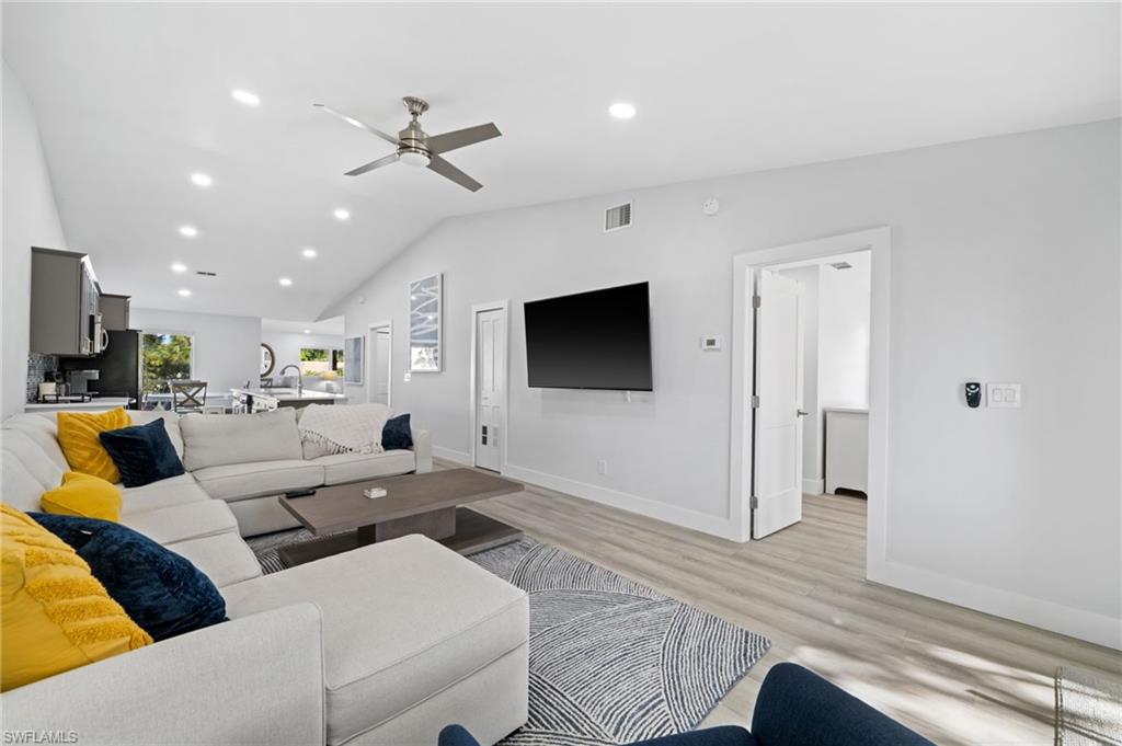Living area with light wood-type flooring, a ceiling fan, recessed lighting, and vaulted ceiling