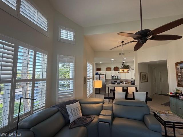 Living room featuring ceiling fan and a high ceiling