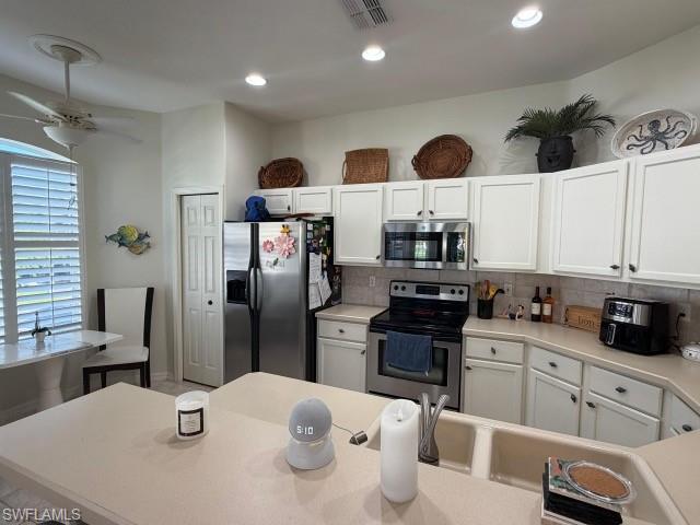 Kitchen with light countertops, white cabinetry, stainless steel appliances, decorative backsplash, and recessed lighting