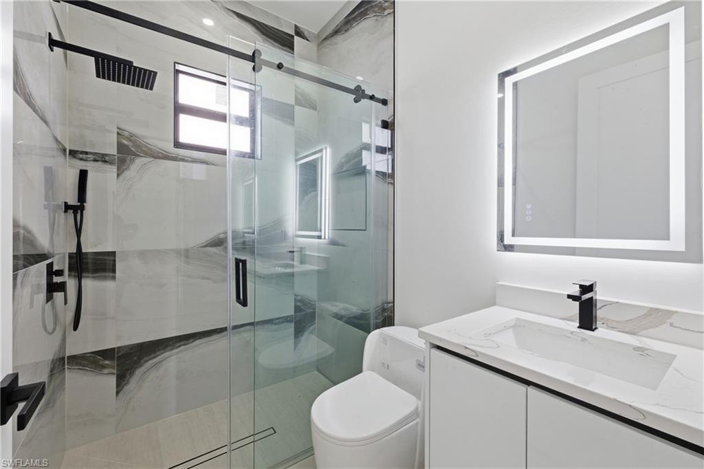 Bathroom featuring a marble finish shower and vanity