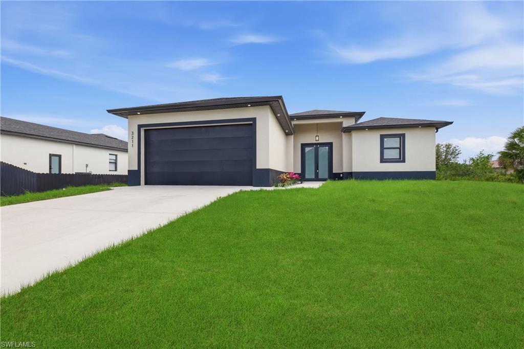 Prairie-style house with driveway, a garage, a front yard, stucco siding, and french doors