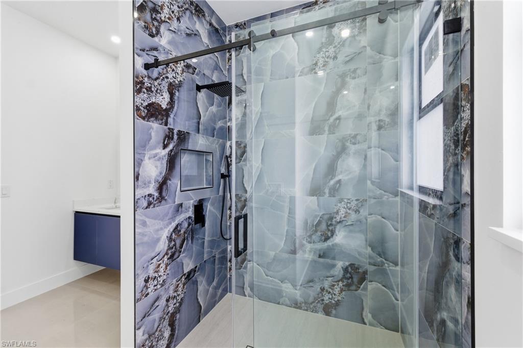 Bathroom featuring vanity and a marble finish shower