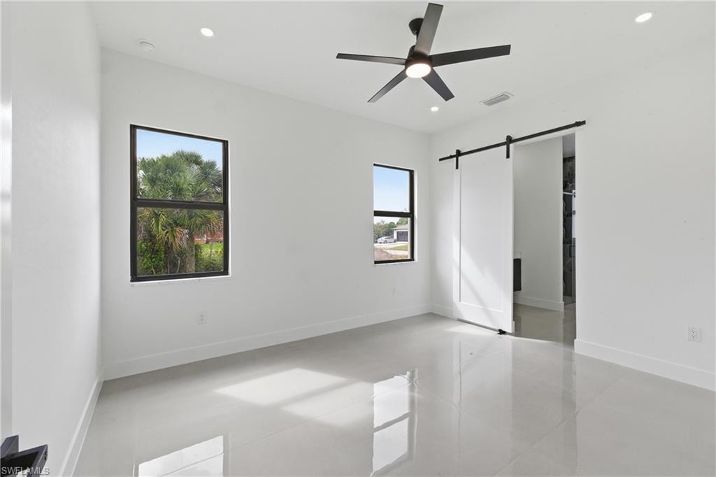 Unfurnished bedroom featuring a barn door, a ceiling fan, and recessed lighting
