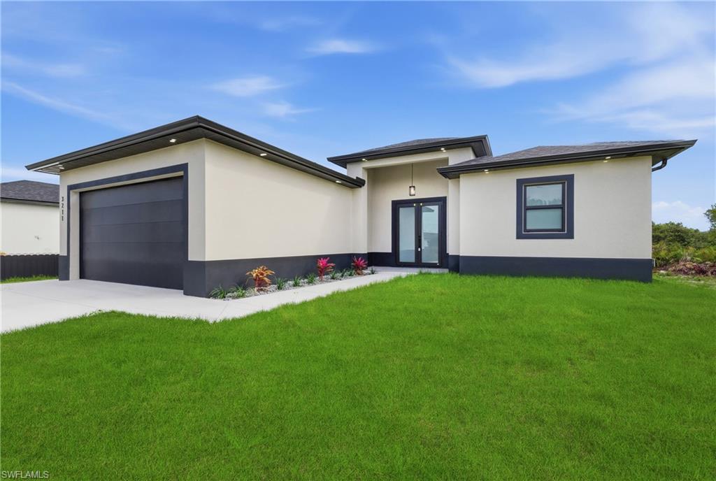 Prairie-style home with a front lawn, french doors, a garage, driveway, and stucco siding
