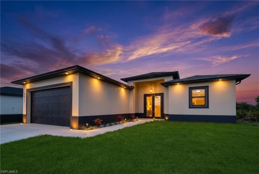 Prairie-style house with a front lawn, a garage, concrete driveway, and stucco siding