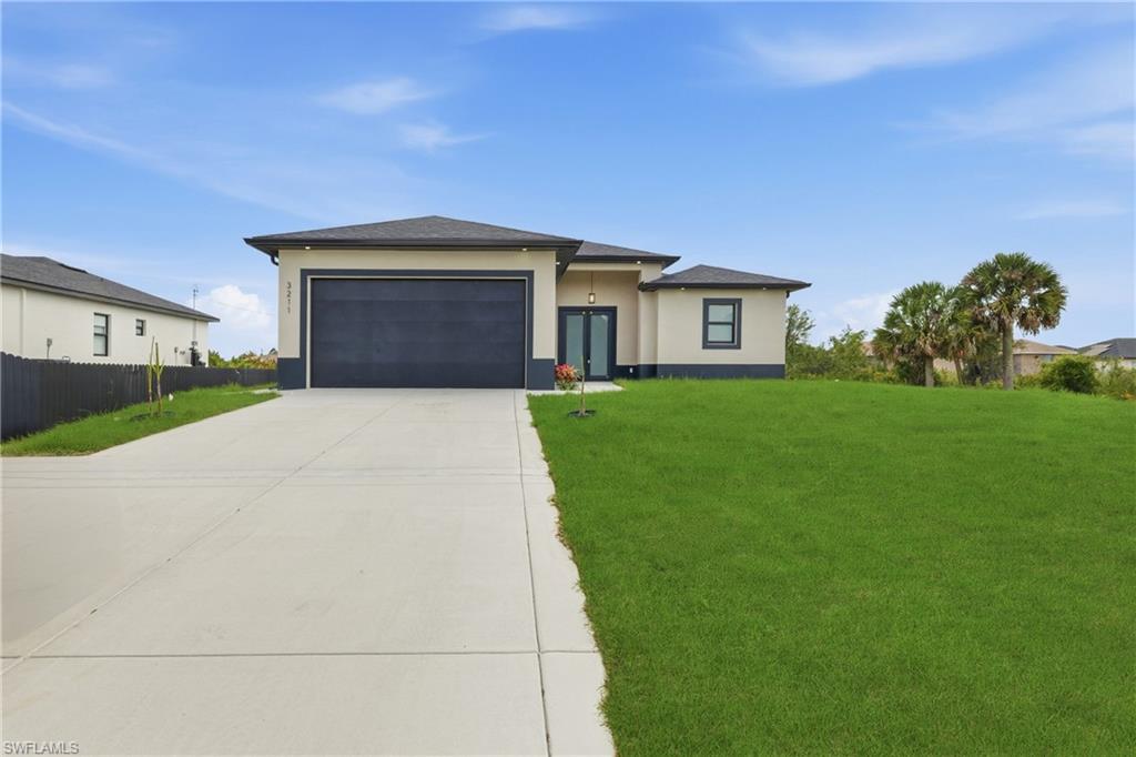 Prairie-style home with a front lawn, a garage, stucco siding, and concrete driveway