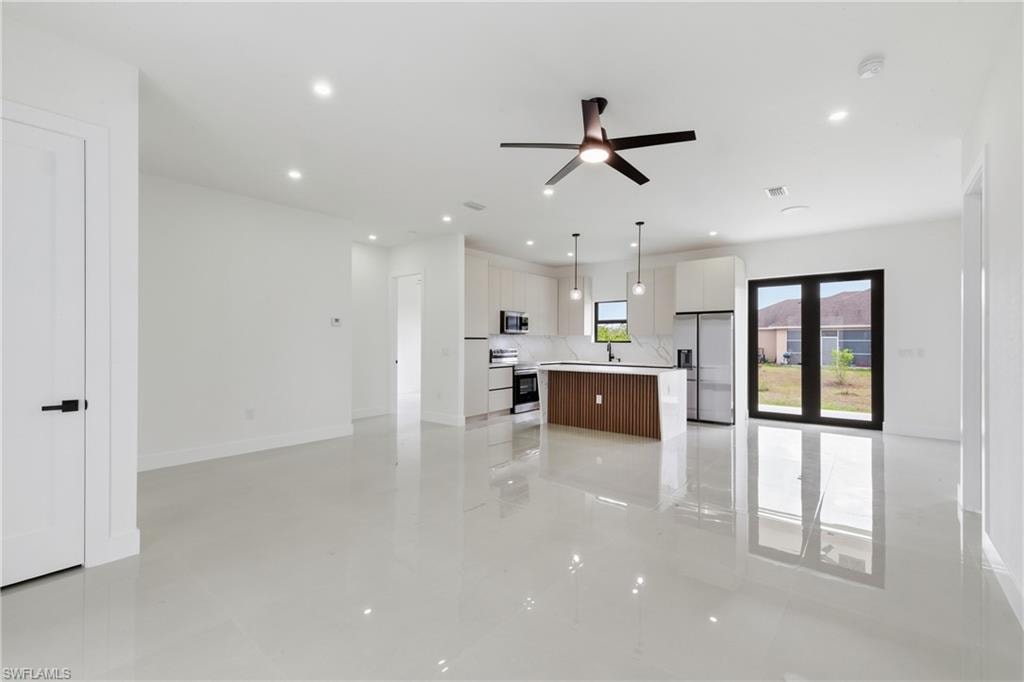 Unfurnished living room with ceiling fan and recessed lighting