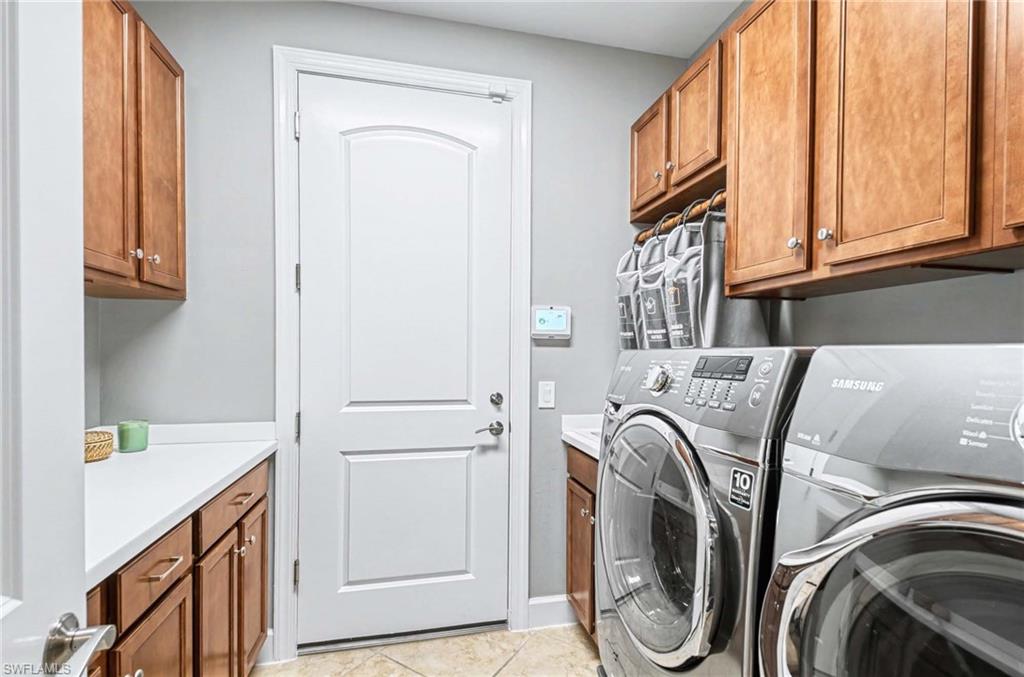 Laundry area featuring cabinet space, washing machine and dryer, and light tile patterned floors