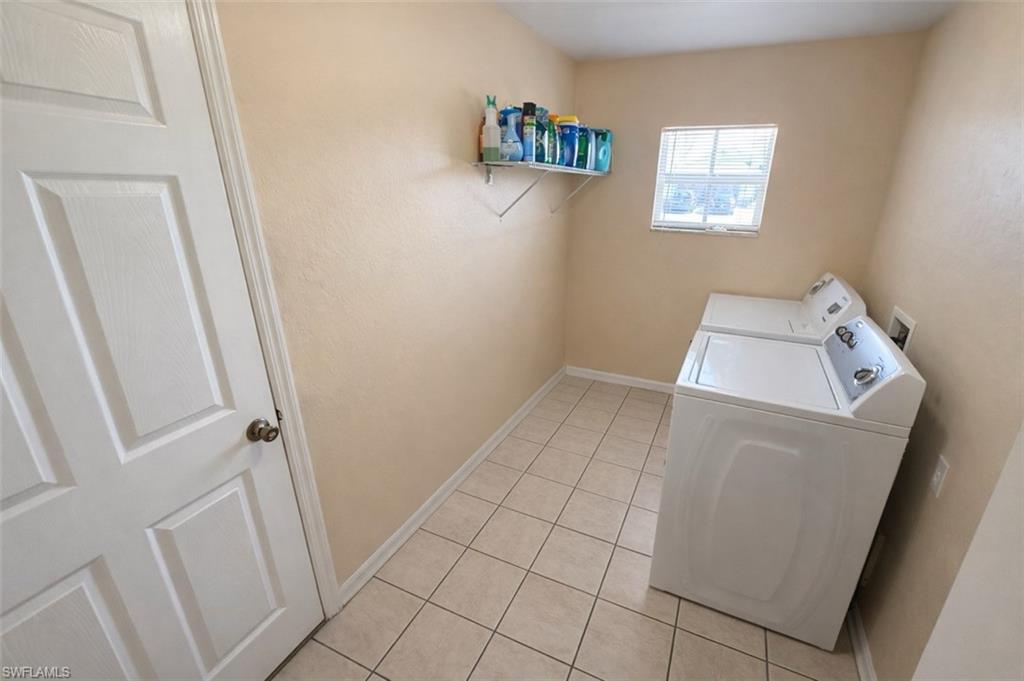 Laundry room featuring light tile patterned flooring and washing machine and clothes dryer