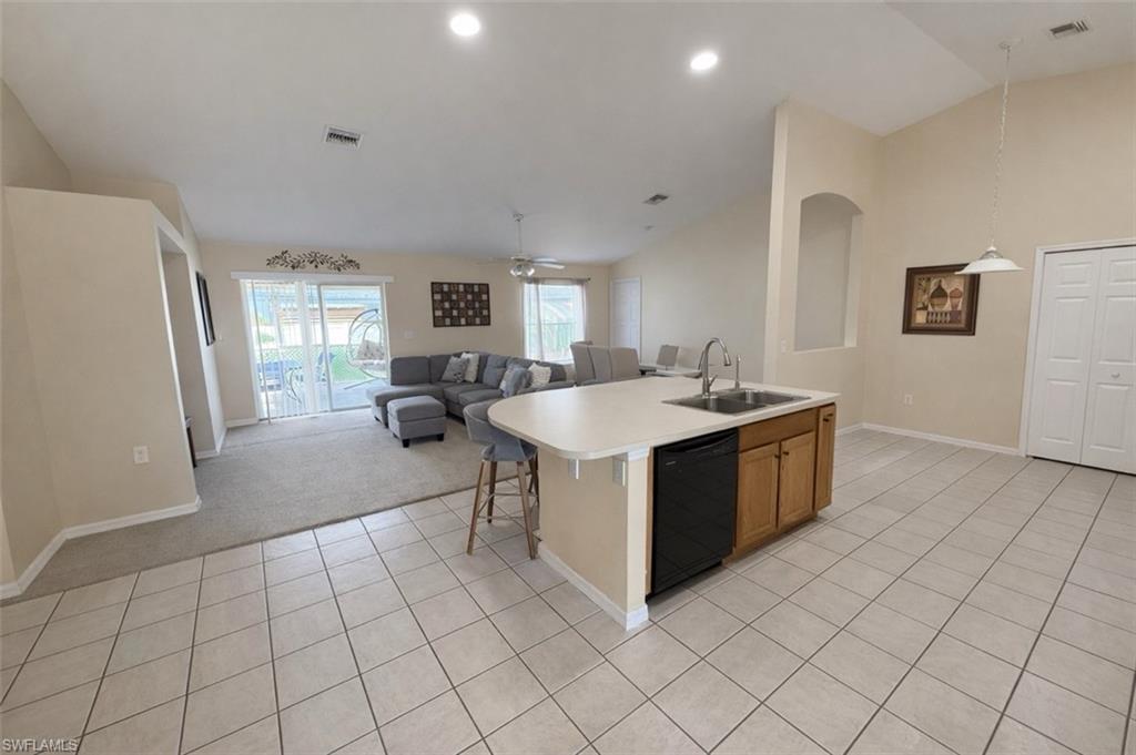 Kitchen featuring lofted ceiling, open floor plan, light countertops, ceiling fan, and dishwasher